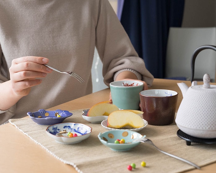 A woman eats apple and drink tea in Celadon cup of amabro