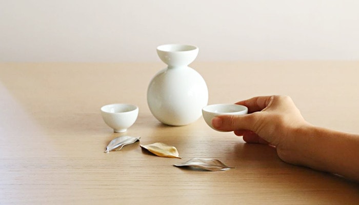 A woman has sake cup of glossy Shuki daruma