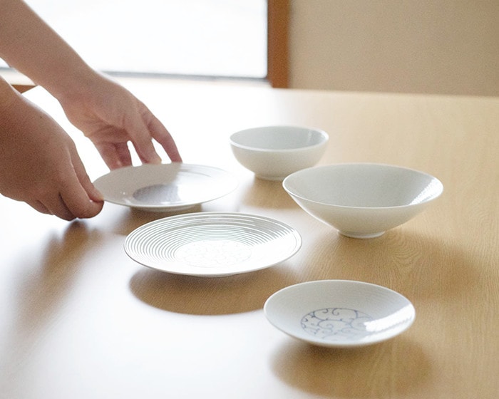 A woman is putting plates of Japanese dishware set