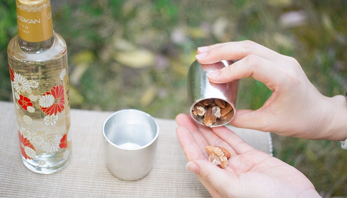 Nuts in a sake bowl of FUTAE. Sake and another sake bowl on the place mat