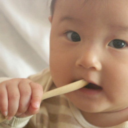 A baby is using wooden baby spoon Mukuri spoon