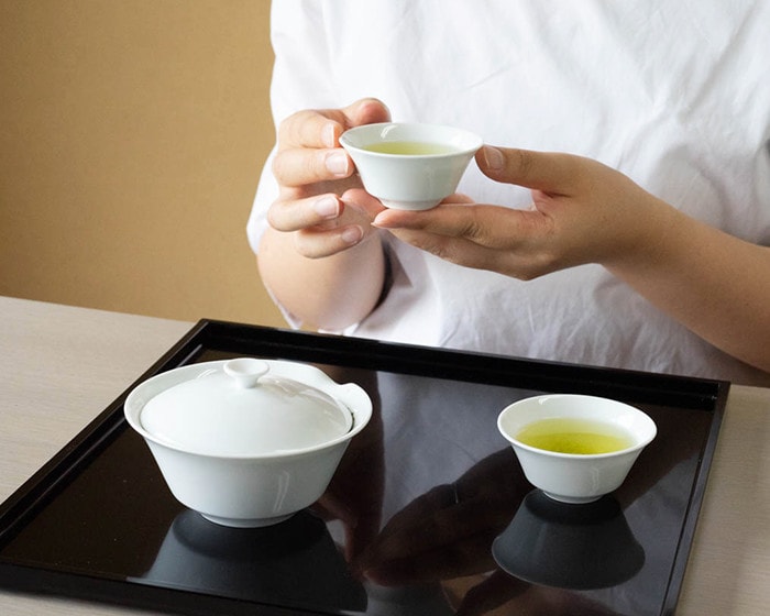 A woman is drinking tea brewed by Houhin teapot